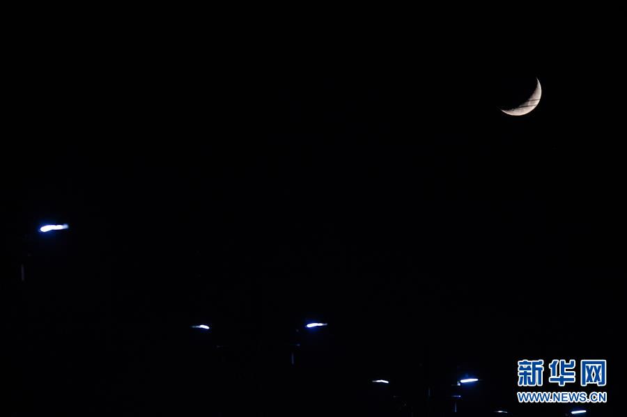 11月19日，在北京亦庄镇，弯弯的月亮挂在天空，与路灯相互辉映。 新华社记者 彭子洋 摄