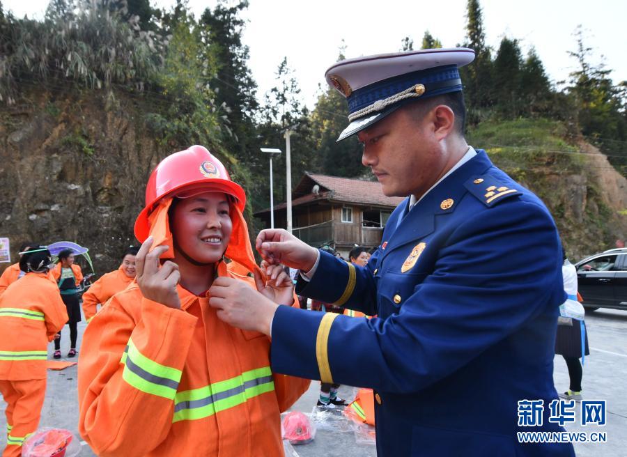 11月19日，乌英苗寨女子志愿消防队队员（左）学习穿戴消防服装。当日，在广西融水苗族自治县消防救援大队的支持下，该县杆洞乡党鸠村乌英苗寨成立了女子志愿消防队。乌英苗寨是桂黔交界的古村落，村民住房都是木结构吊脚楼。为了进一步做好村寨火灾预防和突发火灾警情处置工作，并结合青壮年大多外出打工的实际，乌英苗寨决定组建女子志愿消防队。女子志愿消防队将义务开展日常消防安全检查、消防安全宣传教育等工作，保护村民的生命财产安全。新华社记者 黄孝邦 摄