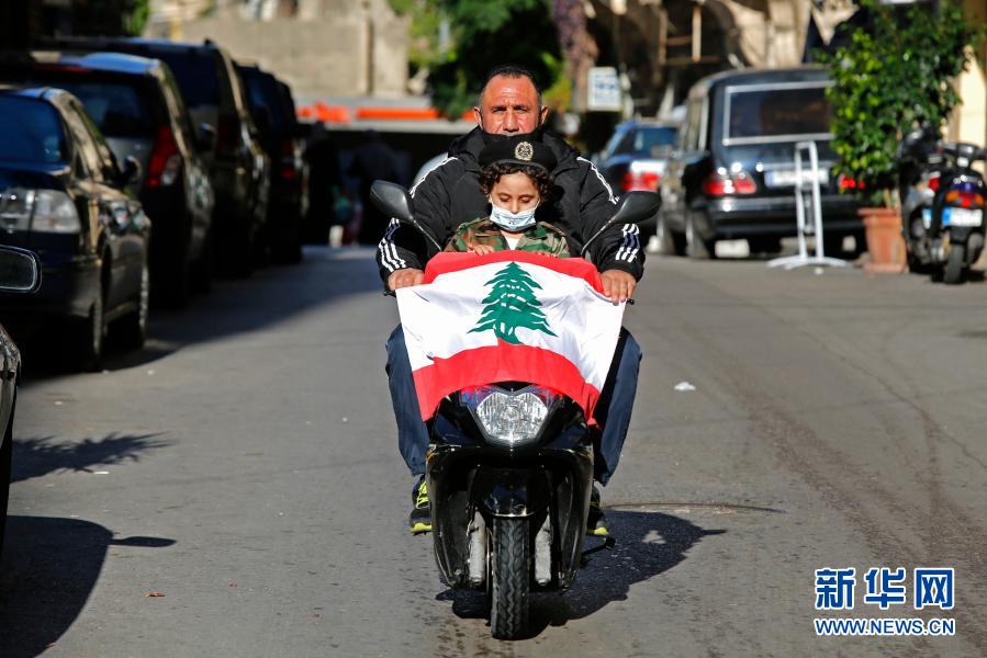 11月22日，在黎巴嫩首都贝鲁特，行人的车头挂着黎巴嫩国旗。11月22日是黎巴嫩独立日。因疫情原因，黎巴嫩今年不仅取消了一切庆祝活动，而且当天恰逢周日，所有车辆按防疫规定禁止出行。新华社发（比拉尔·贾维希摄）