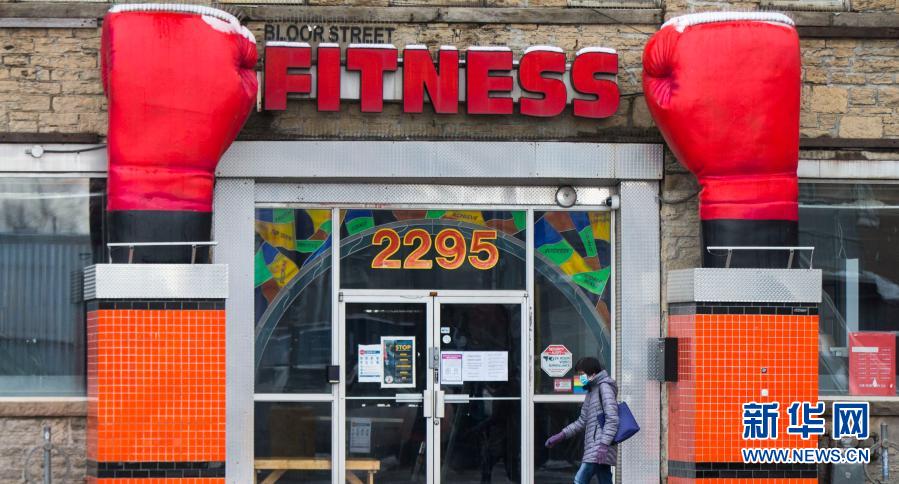 11月23日，在加拿大多伦多，一名戴口罩的行人路过一家关闭的健身俱乐部。当日，加拿大新增新冠确诊病例5119例，多伦多等地因疫情上升再度“封城”。新华社发（邹峥摄）