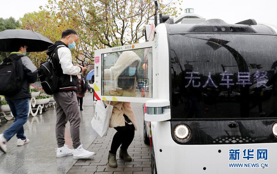 11月26日，顾客完成扫码支付后从无人餐车内取出食物。近日，一种可以远程控制行驶并自主卖餐的移动无人餐车亮相上海张江科学城，为上班族提供快捷的用餐服务。无人餐车装备全方位感应雷达及摄像头，可实现远程操控并兼顾行驶安全。用户在车头前挥挥手，无人餐车就会停车。用户在车身购物屏幕上点选商品，扫描车身上方的二维码，支付取货一次完成。新华社记者 方喆 摄