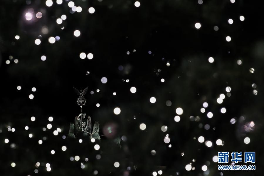 这是11月29日在德国首都柏林拍摄的圣诞树灯饰后的勃兰登堡门雕塑。当日，德国柏林勃兰登堡门前的圣诞树被灯饰点亮。今年柏林多处圣诞市场及相关庆祝活动由于新冠疫情被取消。新华社记者 单宇琦 摄