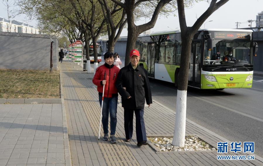 12月1日，张广明（右）在公交站接盲人朋友张朝华。79岁的张广明是居住在北京市丰台区宛平城地区的退休党员，多年来，张广明义务帮助他家附近的盲文出版社工作的多位盲人，接送他们上下班、带他们在周边公园散步聊天等，被盲人朋友们称为“我们的眼睛”。新华社记者 李欣 摄
