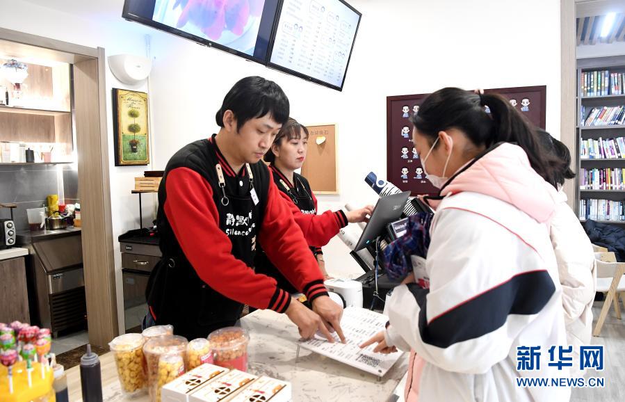 西安“静默咖啡”的店员李涛和曹瑞华为顾客点单（12月1日摄）。新华社记者 刘潇摄