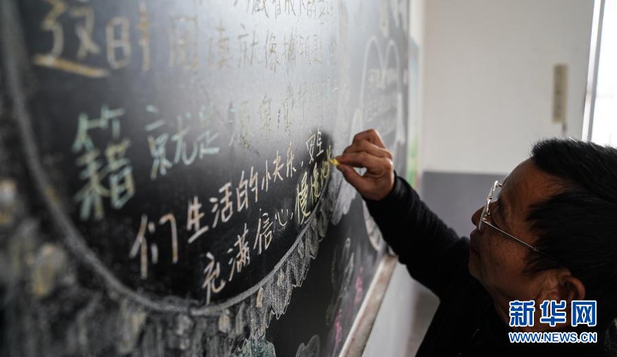 江国南在教室写黑板报（12月3日摄）。新华社记者 胡晨欢 摄