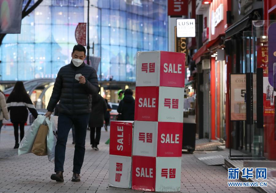 12月8日，在韩国首尔明洞，一名戴口罩的男子经过一家打折店铺。新冠疫情近期在韩国再次出现反弹且持续扩散，韩国政府从8日零时起再次上调全国保持社交距离防疫级别，进一步收紧防疫措施。从8日起，首尔、仁川、京畿道等首都圈地区的防疫级别从2级提升至2.5级，其他非首都圈地区从1.5级提升至2级，暂定实施3周。新华社记者 王婧嫱 摄