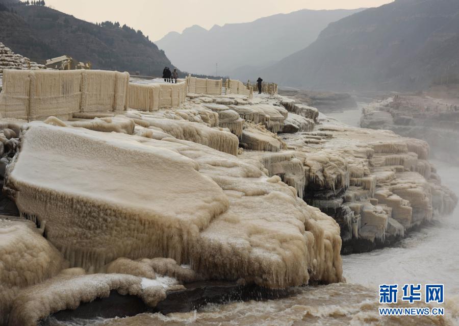 12月9日，游客在山西吉县黄河壶口瀑布景区欣赏“冰瀑玉壶”壮美景观。随着气温骤降，位于山西吉县和陕西宜川县交界处的黄河壶口瀑布出现壮美的“冰瀑玉壶”景观，吸引了众多游客。新华社发（吕桂明 摄）