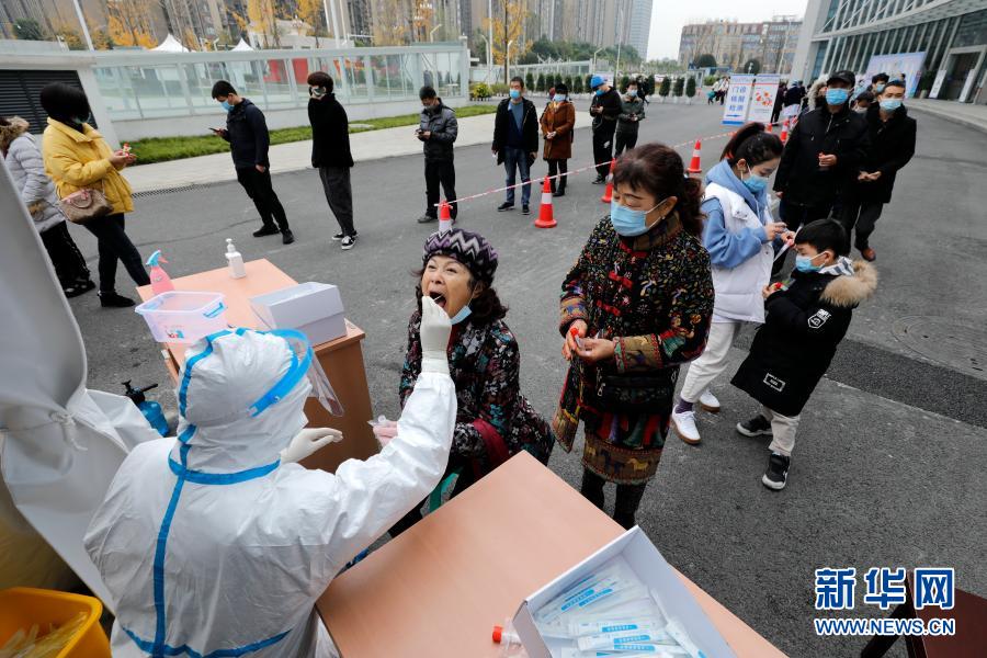 12月10日，在郫都区中医医院核酸检测点，医务人员对居民进行核酸取样。自12月7日成都市郫都区新增新冠肺炎本土确诊病例以来，郫都区中医医院进入24小时连轴转状态。该院信息科技术人员通宵达旦设计上线核酸检测微信小程序，方便人们在手机上查看检测报告。核酸检测室的14名检测员24小时3班倒，日均完成2000多份核酸检测。“拼尽全力与病毒争分夺秒！”检测科主任孔丽蕊说。新华社记者 沈伯韩 摄