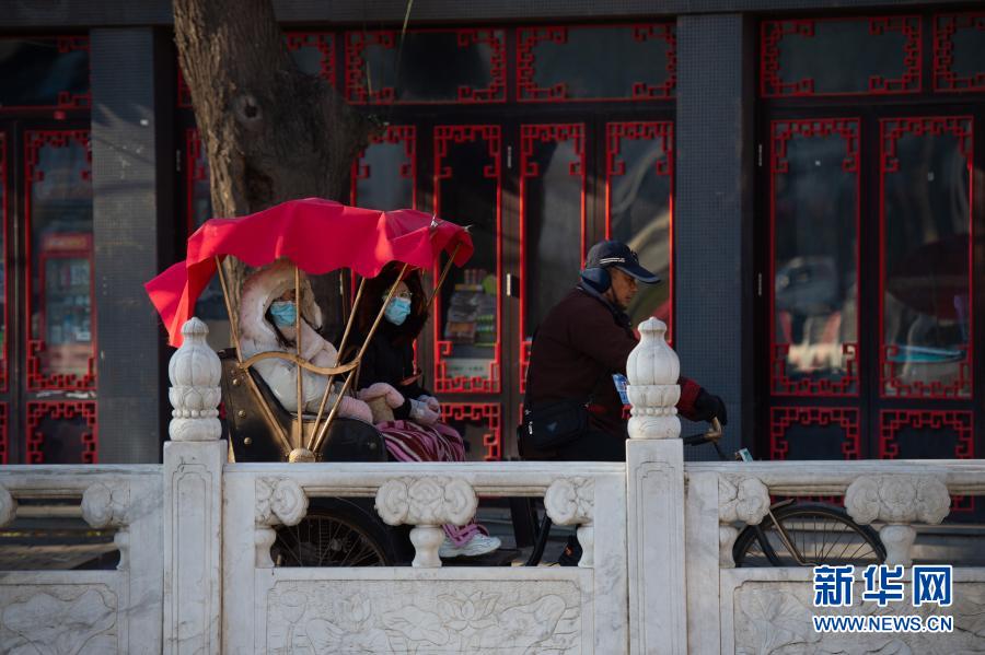 12月13日，游人乘坐人力三轮车欣赏什刹海风景。当日，天气晴好，位于北京东城区的什刹海景区艳阳高照，沧桑的古建筑、结冰的湖水、悠闲的游人……呈现一幅别样的古都冬景图。新华社记者 陈钟昊 摄