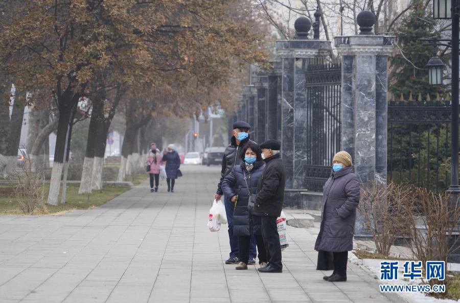 12月14日，在乌兹别克斯坦首都塔什干，市民佩戴口罩在街边等待公交车。新华社发（扎法尔摄）
