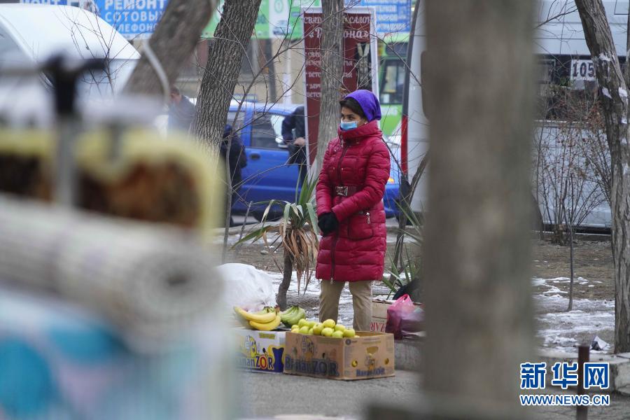 12月14日，在乌兹别克斯坦首都塔什干，商贩佩戴口罩在街边售卖水果。新华社发（扎法尔摄）