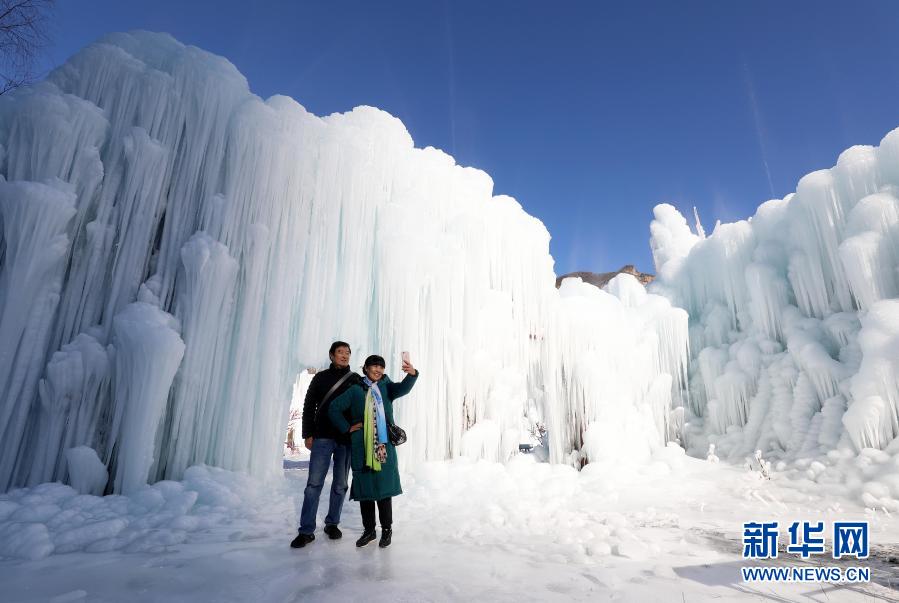 12月16日，在河北省平山县沕沕水景区，游客在冰瀑中拍照游玩。近日，随着天气渐冷，位于太行山区的河北省平山县沕沕水景区内形成了冰瀑景观。山涧被晶莹剔透的冰瀑覆盖，形态各异的冰挂、冰柱为山体增添了一抹亮色。新华社发（梁子栋 摄）