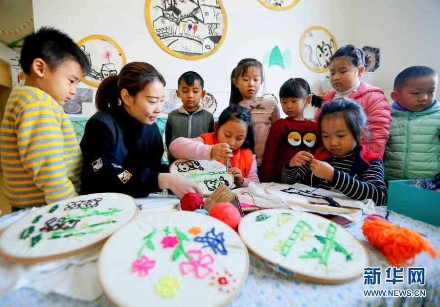 12月17日，青岛市即墨区龙山街道中心幼儿园的孩子们在老师的指导下制作刺绣作品。当日，山东省青岛市即墨区龙山街道中心幼儿园开展“传统文化进课堂”活动。小朋友在当地艺人和老师的指导下，学习柳腔、竹编、刺绣、剪纸等传统艺术，近距离感受传统文化的魅力。新华社发（梁孝鹏摄）