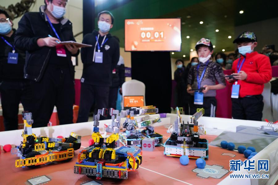 12月20日，在北京中国科学技术馆内举办的2020 Robo Genius人工智能与机器人挑战赛总决赛上，参赛选手（右一、右二）操控机器人完成比赛任务。当日，2020 Robo Genius人工智能与机器人挑战赛总决赛在北京中国科学技术馆举行。在以“火星探索”为主题的比赛场上，来自全国各地的百余支中小学生队伍比拼机器人完成跨区域行动、碎片收集、阀门开启等任务。经过层层淘汰晋级，最终来自河南的卢星皓、江宸宇获得小学组冠军，来自广东的凌深杰、陈天泽获得初中组冠军。新华社记者 陈钟昊 摄