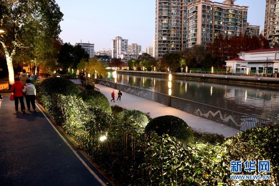 12月20日，游客在苏州河宝成桥附近散步休闲。随着上海苏州河沿河景观工程的有序推近，不少岸线已完成贯通和景观美化提升工程。据悉，2020年底，集绿地、道路景观、亲水平台为一身的苏州河中心城区42公里岸线公共空间将基本实现贯通开放。新华社记者 陈飞 摄