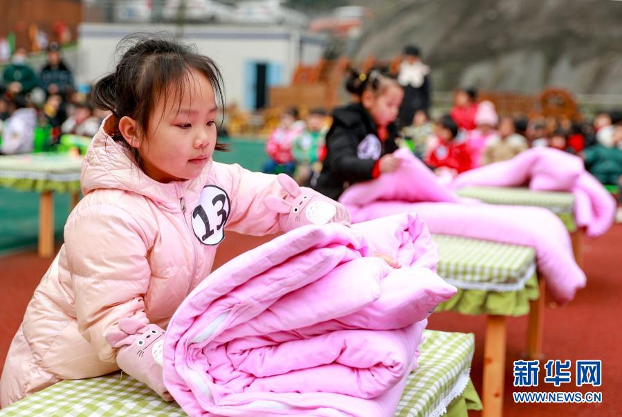 12月21日，四川省华蓥市清溪路幼儿园的小朋友在参加叠被子比赛。当日，华蓥市清溪路幼儿园开展以“生活自理，快乐自立”为主题的幼儿生活技能大赛。幼儿园的小朋友们参加了叠被子、叠衣服、穿鞋子、剥熟鸡蛋及整理书包等项目的比赛。比赛旨在培养孩子们的生活自理能力和良好的生活习惯。新华社发（邱海鹰 摄）