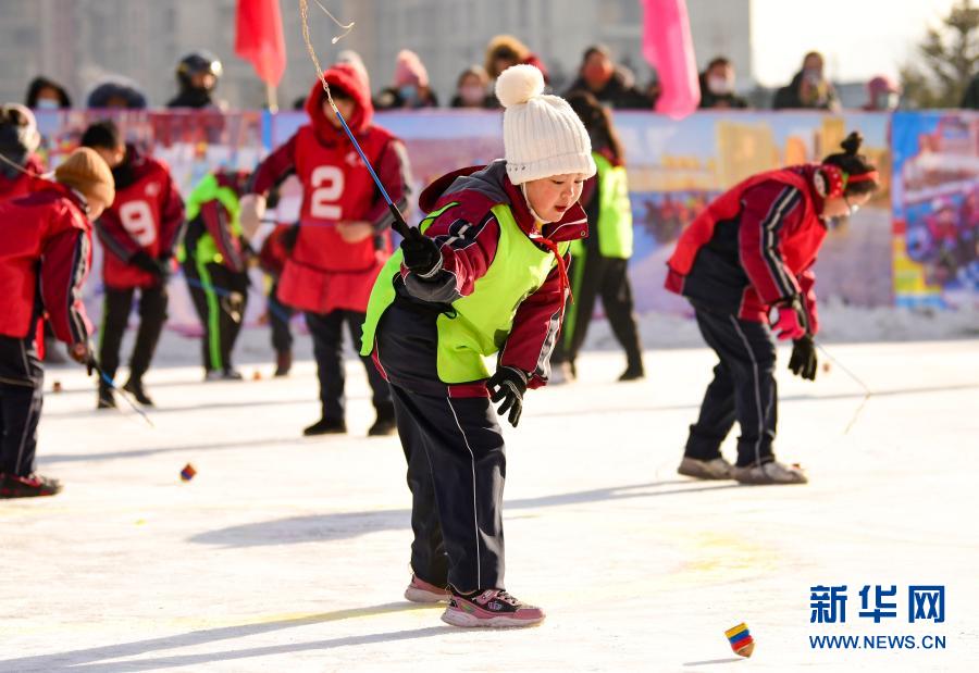 12月21日，乌兰察布市集宁区建国四路小学学生在校园冰雪文化节上参加冰上抽陀螺运动。新华社发（王正 摄）