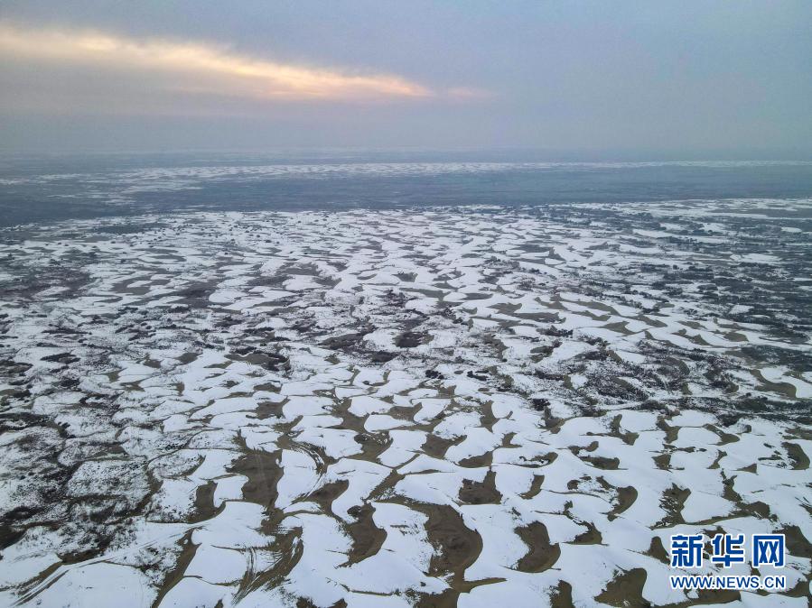 这是12月27日拍摄的塔克拉玛干沙漠（无人机照片）。在新疆岳普湖县达瓦昆沙漠旅游风景区内，塔克拉玛干沙漠在皑皑白雪映衬下更添秀色，黄沙与白雪相映成趣，景色如画。新华社记者 高晗 摄