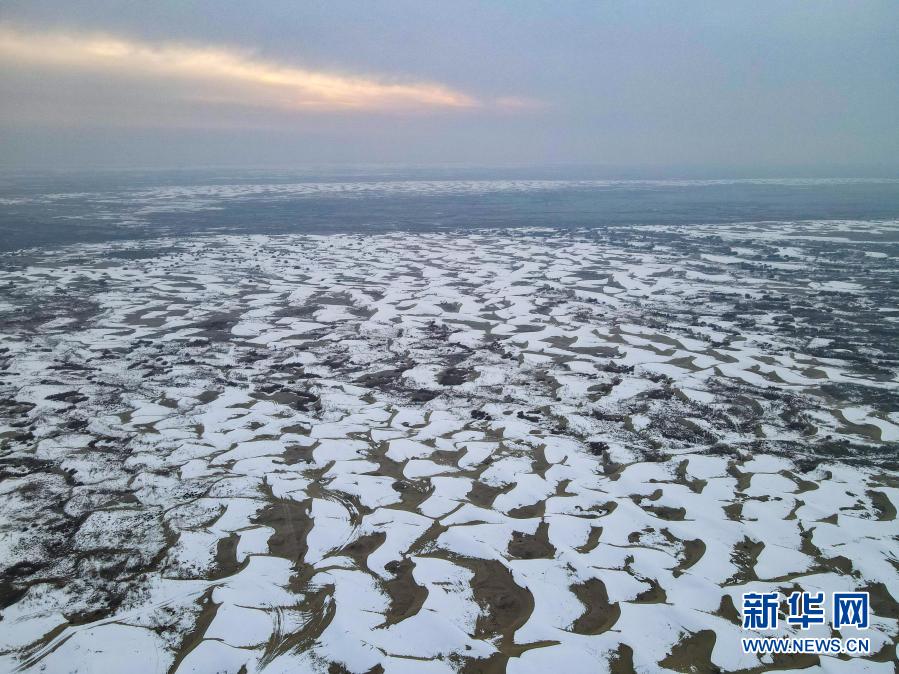 这是12月27日拍摄的塔克拉玛干沙漠（无人机照片）。在新疆岳普湖县达瓦昆沙漠旅游风景区内，塔克拉玛干沙漠在皑皑白雪映衬下更添秀色，黄沙与白雪相映成趣，景色如画。新华社记者 高晗 摄