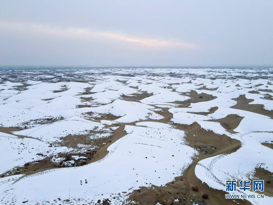 这是12月27日拍摄的塔克拉玛干沙漠（无人机照片）。在新疆岳普湖县达瓦昆沙漠旅游风景区内，塔克拉玛干沙漠在皑皑白雪映衬下更添秀色，黄沙与白雪相映成趣，景色如画。新华社记者 高晗 摄