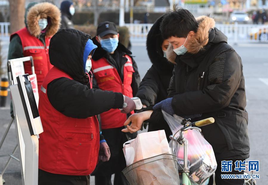 12月29日，在北京市顺义区旺泉街道宏城花园社区出入口，社区工作人员（前左）为居民测量体温。新华社记者 任超 摄