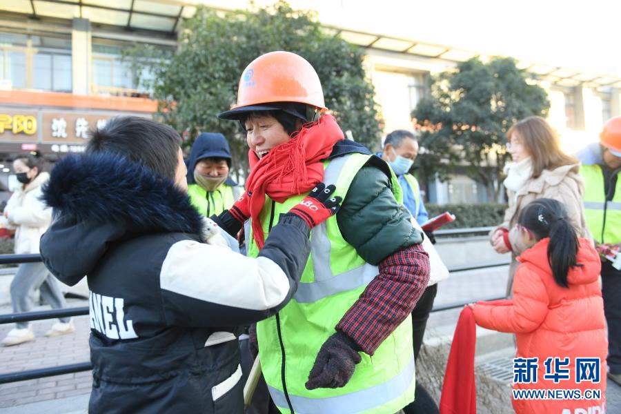 12月31日，八里店镇中心幼儿园的师生为街头的环卫工人系上围巾。当日清晨，浙江湖州吴兴区八里店镇三合片区开展冬日送温暖活动，志愿者和幼儿园师生为在道路、社区忙碌的环卫工人送来早餐、手套和围巾。新华社记者 翁忻旸 摄