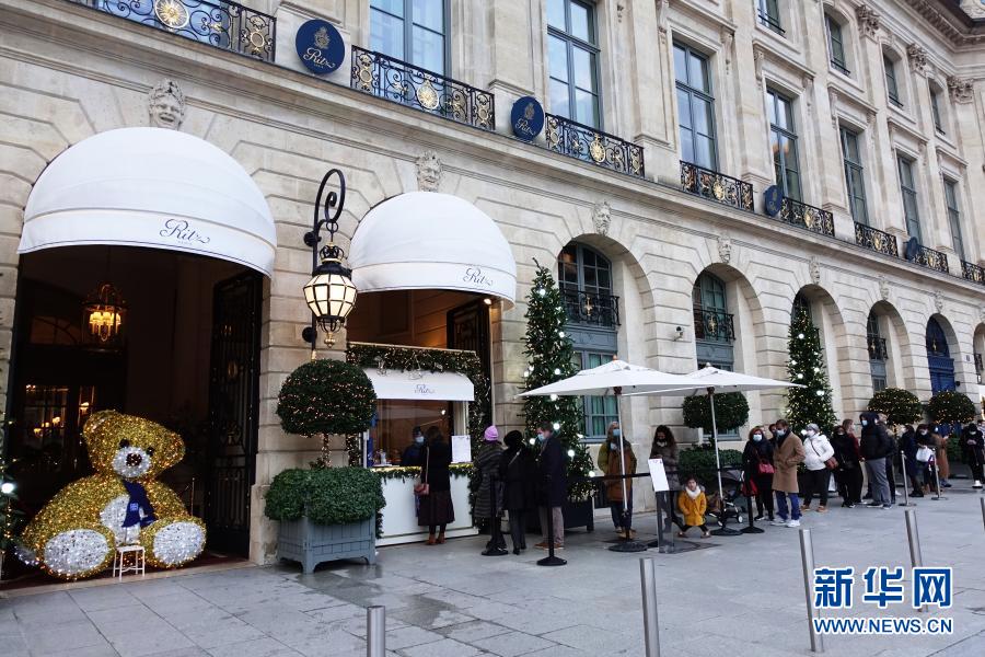 2020年12月31日，人们在法国巴黎一家酒店的外卖甜品窗口处排队。受新冠肺炎疫情影响，巴黎今年的跨年夜不同以往。为防范新冠肺炎疫情，法国各地自20时至次日6时实行宵禁，31日的跨年庆祝活动不被允许。新华社记者高静摄