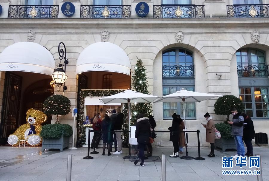 2020年12月31日，人们在法国巴黎一家酒店的外卖甜品窗口处排队。受新冠肺炎疫情影响，巴黎今年的跨年夜不同以往。为防范新冠肺炎疫情，法国各地自20时至次日6时实行宵禁，31日的跨年庆祝活动不被允许。新华社记者高静摄