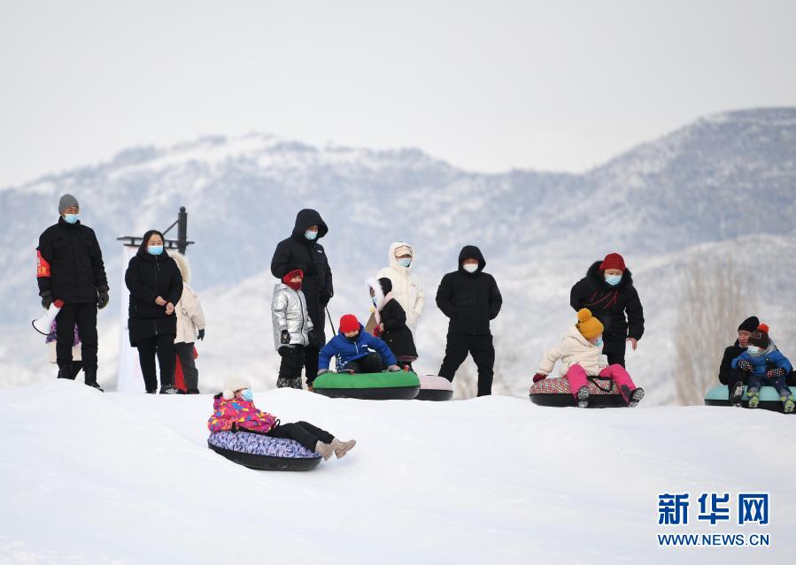2021年1月1日，人们在新疆阿勒泰市桦林公园“桦林冬奥冰雪乐园”雪上项目区玩雪圈。当日是元旦假期第一天，许多市民和游客来到新疆阿勒泰市桦林公园“桦林冬奥冰雪乐园”体验雪圈、狗拉雪橇、雪地履带车等趣味冰雪项目，欢度佳节。新华社记者 沙达提 摄