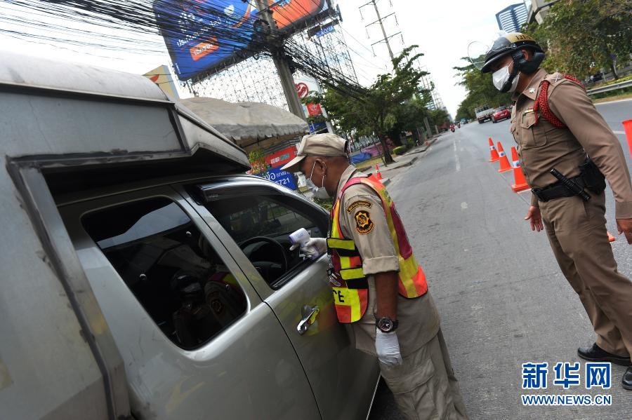 1月5日，警察在泰国曼谷的一处防疫检查站测量过往车辆内人员的体温。泰国自1月4日起开始对包括曼谷在内的全国28个府级行政区实施为期1个月的严格管制措施，以控制疫情快速蔓延趋势。新华社发（拉亨 摄）