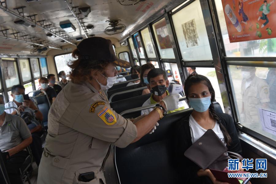 1月5日，警察在泰国曼谷的一处防疫检查站测量公交车内乘客的体温。泰国自1月4日起开始对包括曼谷在内的全国28个府级行政区实施为期1个月的严格管制措施，以控制疫情快速蔓延趋势。新华社发（拉亨 摄）