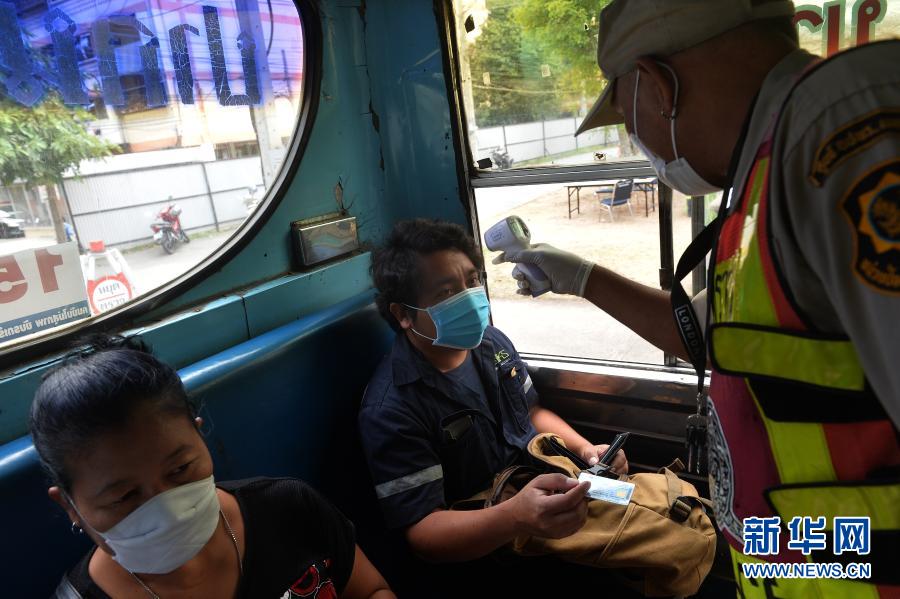 1月5日，警察在泰国曼谷的一处防疫检查站测量公交车内乘客的体温。泰国自1月4日起开始对包括曼谷在内的全国28个府级行政区实施为期1个月的严格管制措施，以控制疫情快速蔓延趋势。新华社发（拉亨 摄）