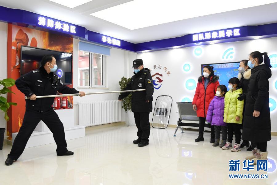 1月10日，在北京市公安局海淀分局永定路派出所第三社区警务工作站展示区，社区民警屈超直（左一）与安保人员向社区居民展示警用装备的用法。当日是首个中国人民警察节，在做好疫情防控的前提下，北京市公安局海淀分局永定路派出所第三社区警务工作站举办警务开放日活动。社区居民在警务工作站展示区通过社区民警的介绍了解防盗、防诈骗、禁毒等知识。新华社记者 任超 摄