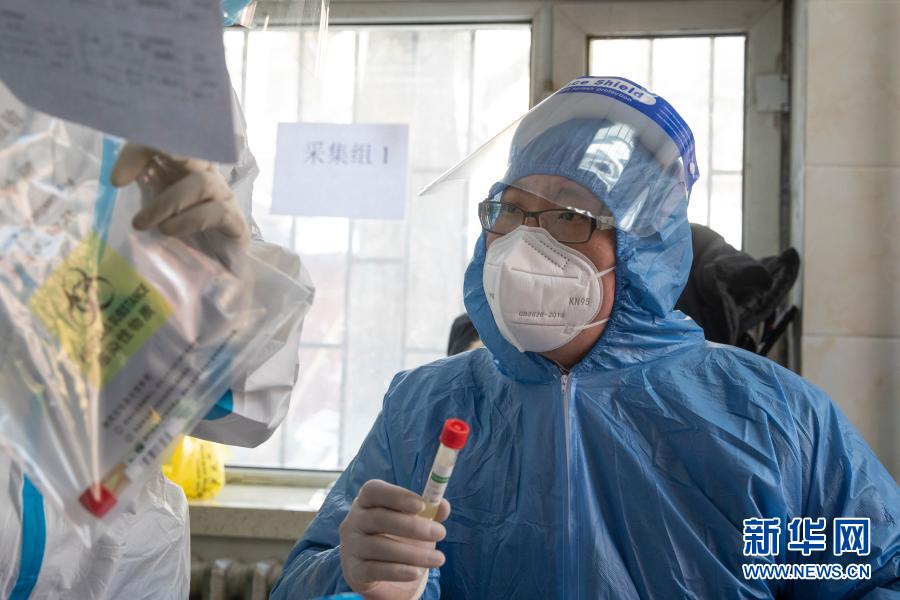 1月14日，医务人员在哈尔滨市香坊区和平街道办事处亚麻社区核酸采集点采样。新华社发（张涛 摄）