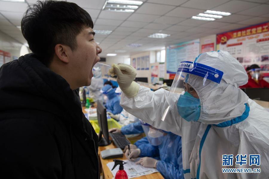 1月14日，医务人员在哈尔滨市香坊区和平街道办事处亚麻社区核酸采集点采样。新华社发（张涛 摄）