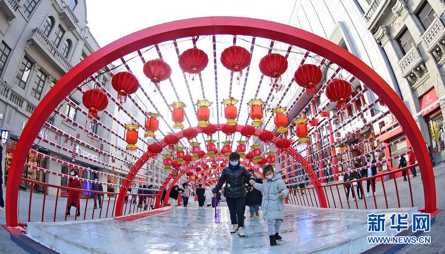 2月1日，在沈阳中街，市民从花灯下走过。春节临近，年味渐浓，在辽宁沈阳中街步行街，福牛艺术雕塑和各色花灯吸引了众多市民观看拍照。新华社记者 杨青 摄