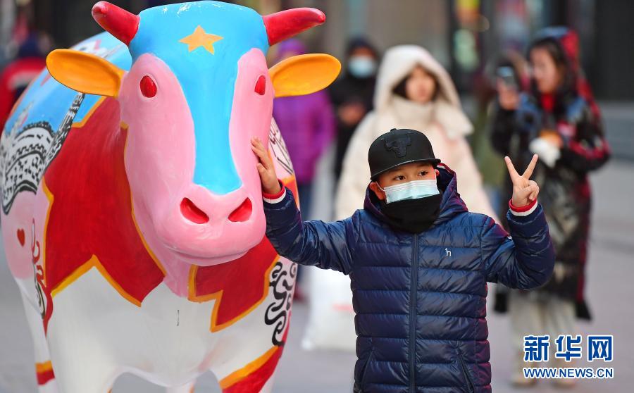 2月1日，一名小朋友在福牛艺术雕塑前拍照。春节临近，年味渐浓，在辽宁沈阳中街步行街，福牛艺术雕塑和各色花灯吸引了众多市民观看拍照。新华社记者 杨青 摄