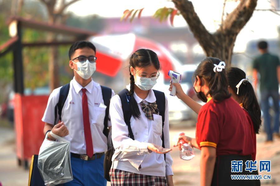 2月1日，学生在泰国曼谷一所学校门口接受体温检测并对手部进行消毒。泰国部分此前因新冠疫情停课的学校于2月1日起开学复课，但仍须严格遵守相关防疫规定。新华社发（拉亨摄）