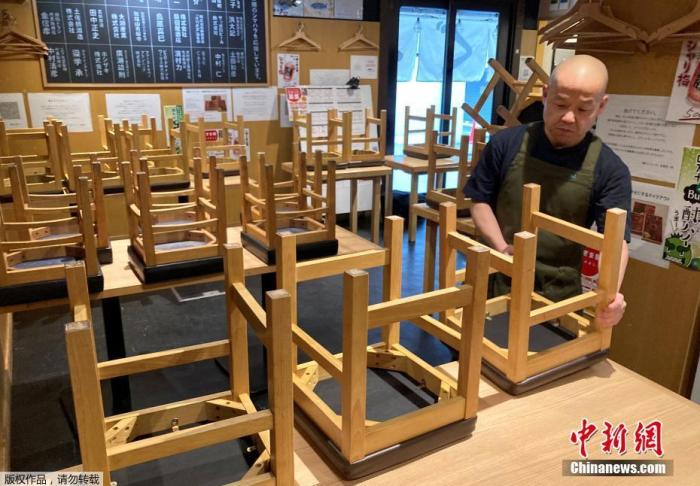 当地时间2021年1月8日,日本东京,一位餐厅老板正在收拾店内的座椅,准备关店。 点击进入下一页