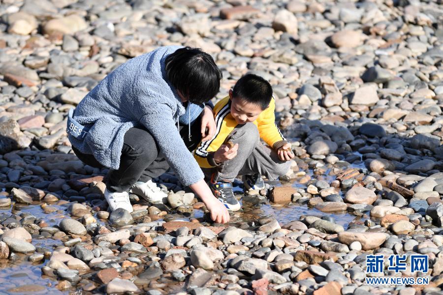　　2月18日，市民带着孩子在黄河兰州段河床上捡石头。　　近日，受黄河上游来水量较少等因素影响，黄河兰州段水位持续下降，部分河床裸露，又恰逢气温回暖，众多市民带着孩子来到黄河边休闲游玩。　　新华社记者 范培珅 摄