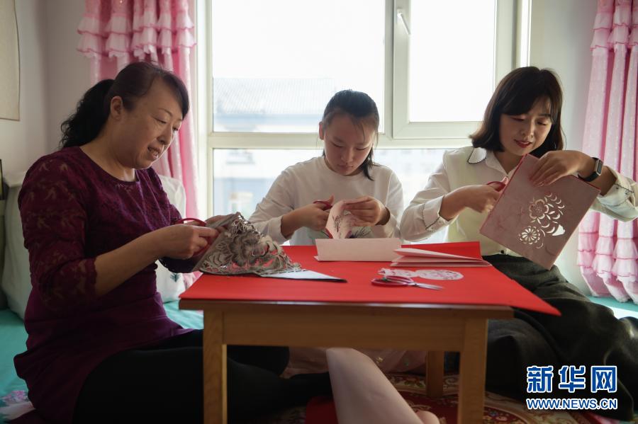 　　2月21日，在乌海市海南区新桥花园，李华（左）与外孙女高宇晨（中）、大女儿谭红叶一起在家中剪纸。新华社记者 李志鹏 摄