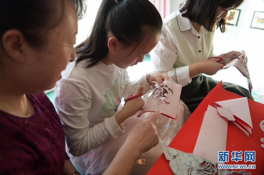 　　2月21日，在乌海市海南区新桥花园，李华（左）在家中指导外孙女高宇晨（中）剪纸。新华社记者 李志鹏 摄