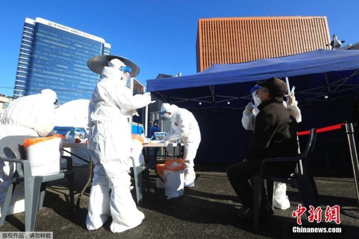 资料图:当地时间2020年12月14日,韩国首尔,医务人员对市民进行新冠病毒检测。 点击进入下一页