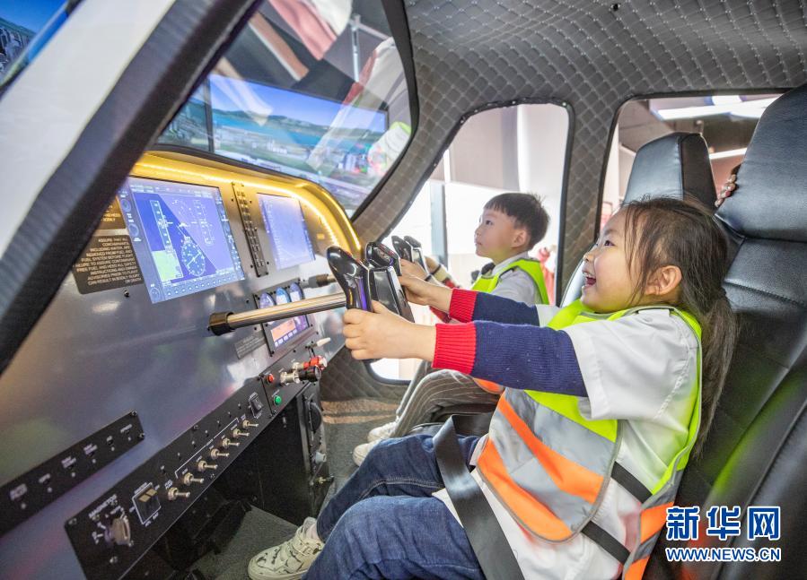 3月20日，小朋友在重庆市沙坪坝区磁器口一家航空飞行体验馆体验动感模拟飞行器。当日，位于重庆市沙坪坝区磁器口的一家航空飞行体验馆举行“小小民航人的一天”航空科普体验活动。体验馆参观、模拟飞行体验、制作橡筋动力模型飞机、模拟飞行员航前绕机检查、空乘应急救生演练以及机务地面引导工作等多种形式的体验学习，激发参加活动孩子们的航空探索热情。新华社记者 黄伟 摄