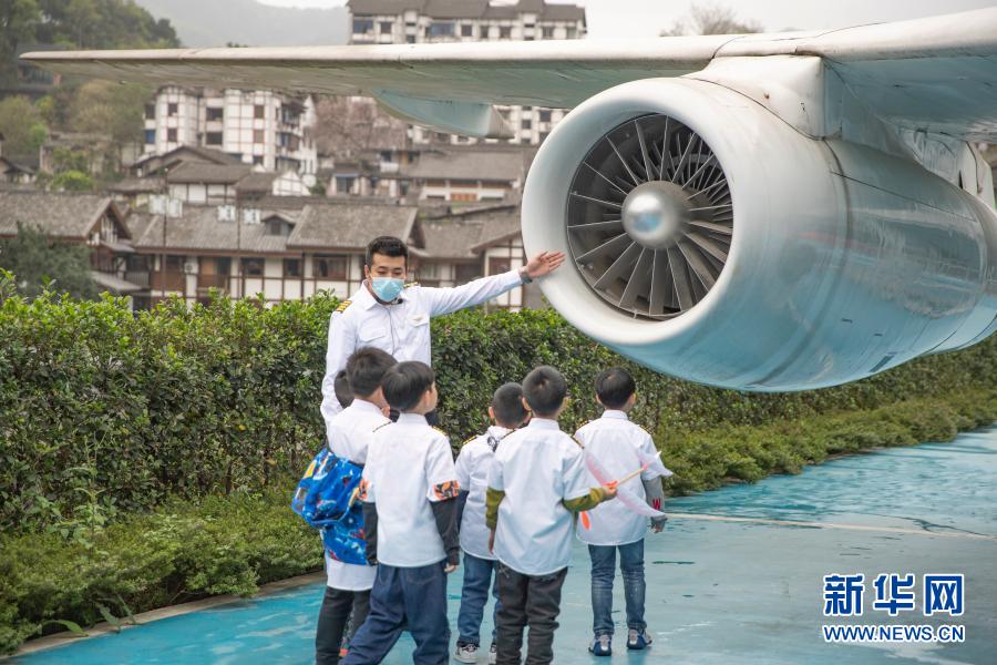 3月20日，在重庆市沙坪坝区磁器口一家航空飞行体验馆，工作人员带领小朋友体验飞行员航前绕机检查，并为小朋友们介绍飞机。新华社记者 黄伟 摄