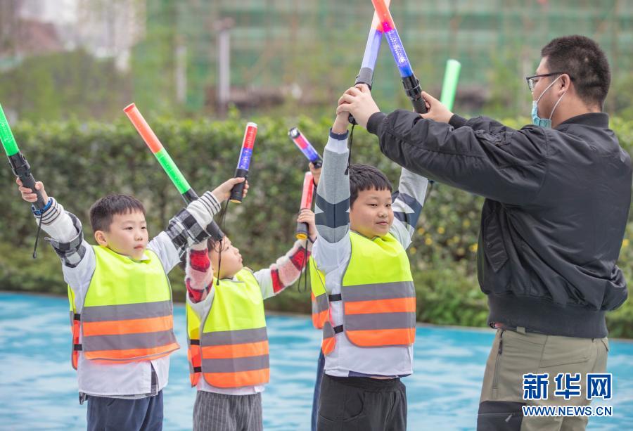 3月20日，在重庆市沙坪坝区磁器口一家航空飞行体验馆，工作人员带领小朋友体验机务地面引导工作。新华社记者 黄伟 摄