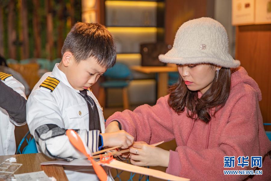 3月20日，在重庆市沙坪坝区磁器口一家航空飞行体验馆，小朋友在家长的帮助下制作橡筋动力模型飞机。新华社记者 黄伟 摄