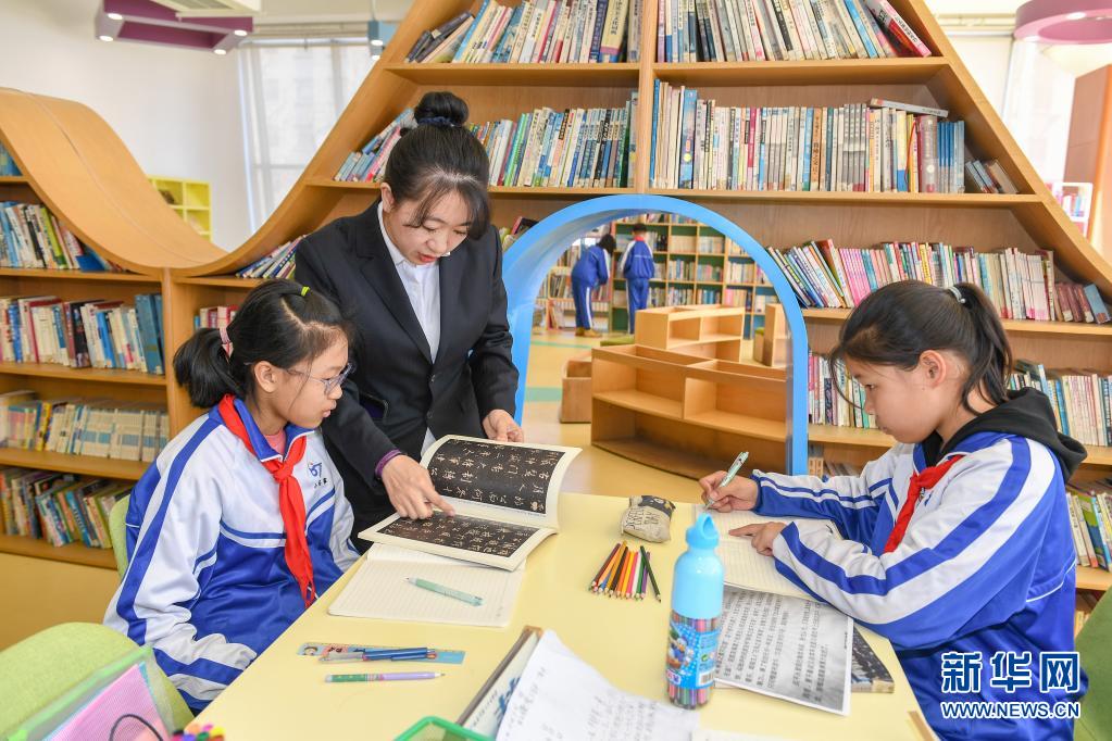 　　3月25日，在长春市第八十七中学图书馆，小学部教师孙铭辅导学生阅读书籍。　　长春市第八十七中学小学部从2018年开始，探索引导学生用绘画加文字的形式完成语文阅读摘抄作业，在不额外增加学生作业负担的前提下，培养学生的阅读习惯。　　新华社记者 张楠 摄