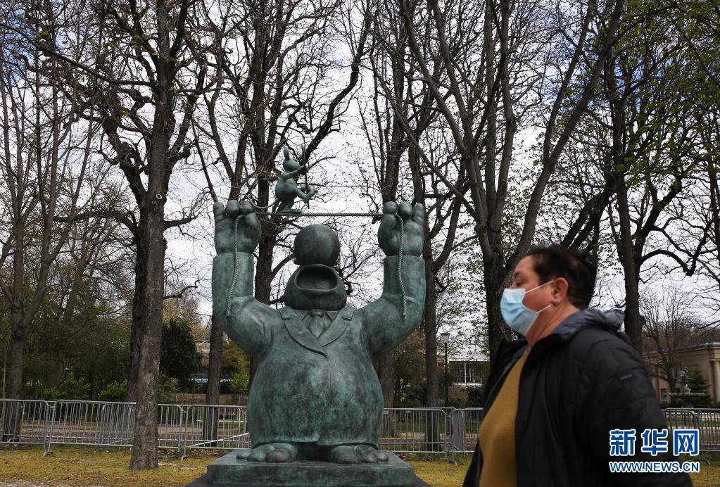 　　3月26日，一名路人经过法国巴黎香榭丽舍大街上的一尊“猫先生”铜像。新华社记者 高静 摄