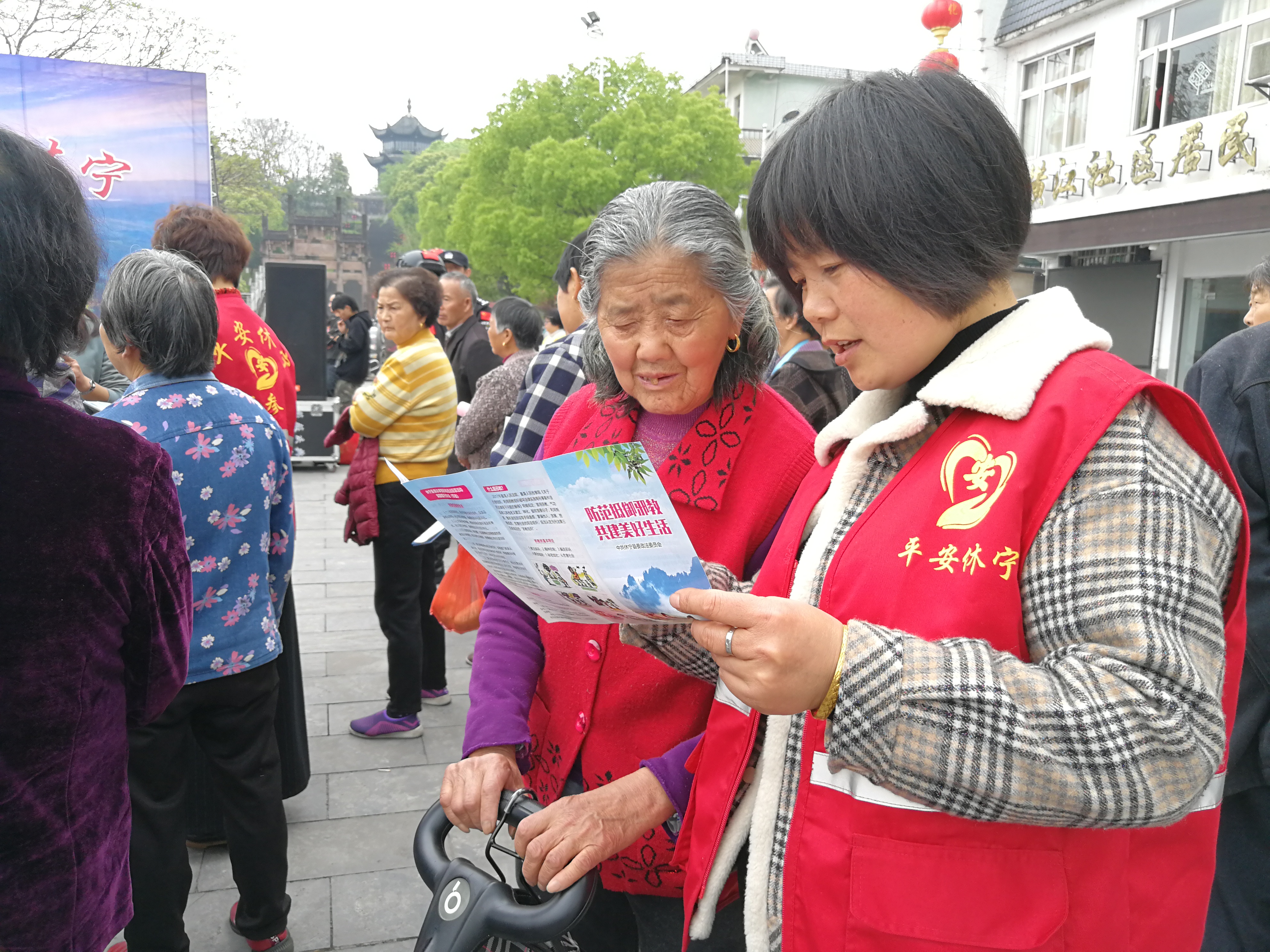 平安休宁志愿者积极参与反邪教法治宣传活动，在活动现场向群众耐心介绍反邪教知识